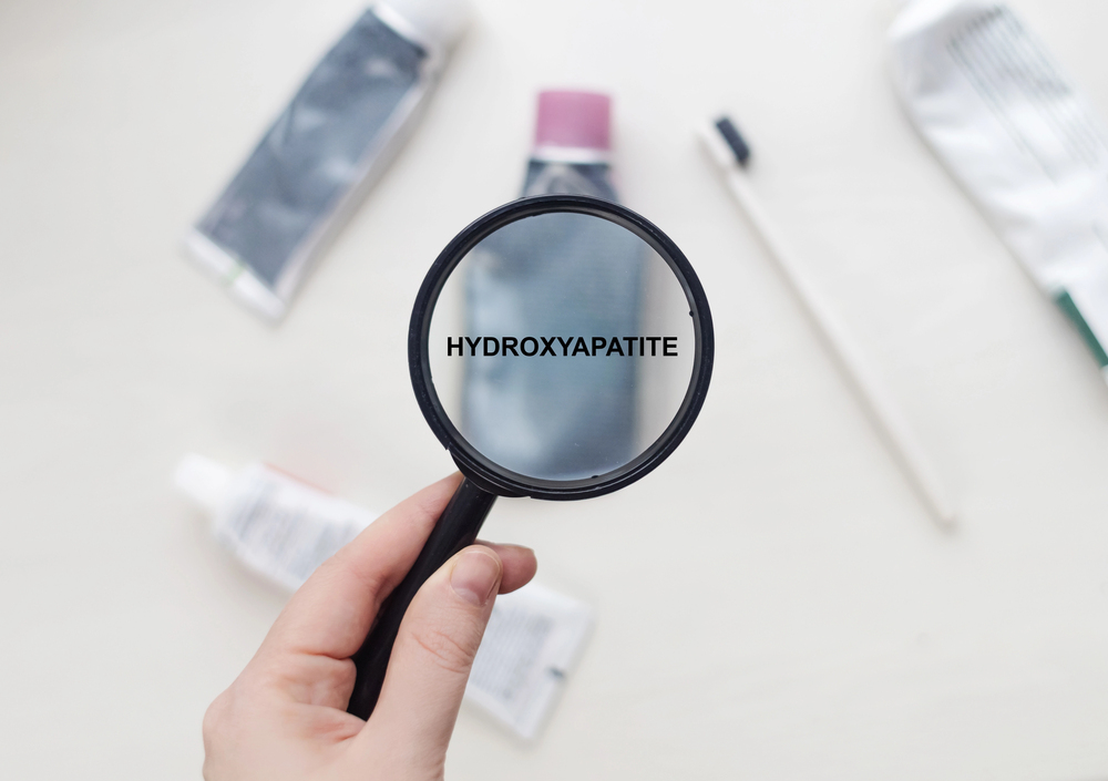 magnifying glass over toothpaste tubes showing word hydroxyapatite